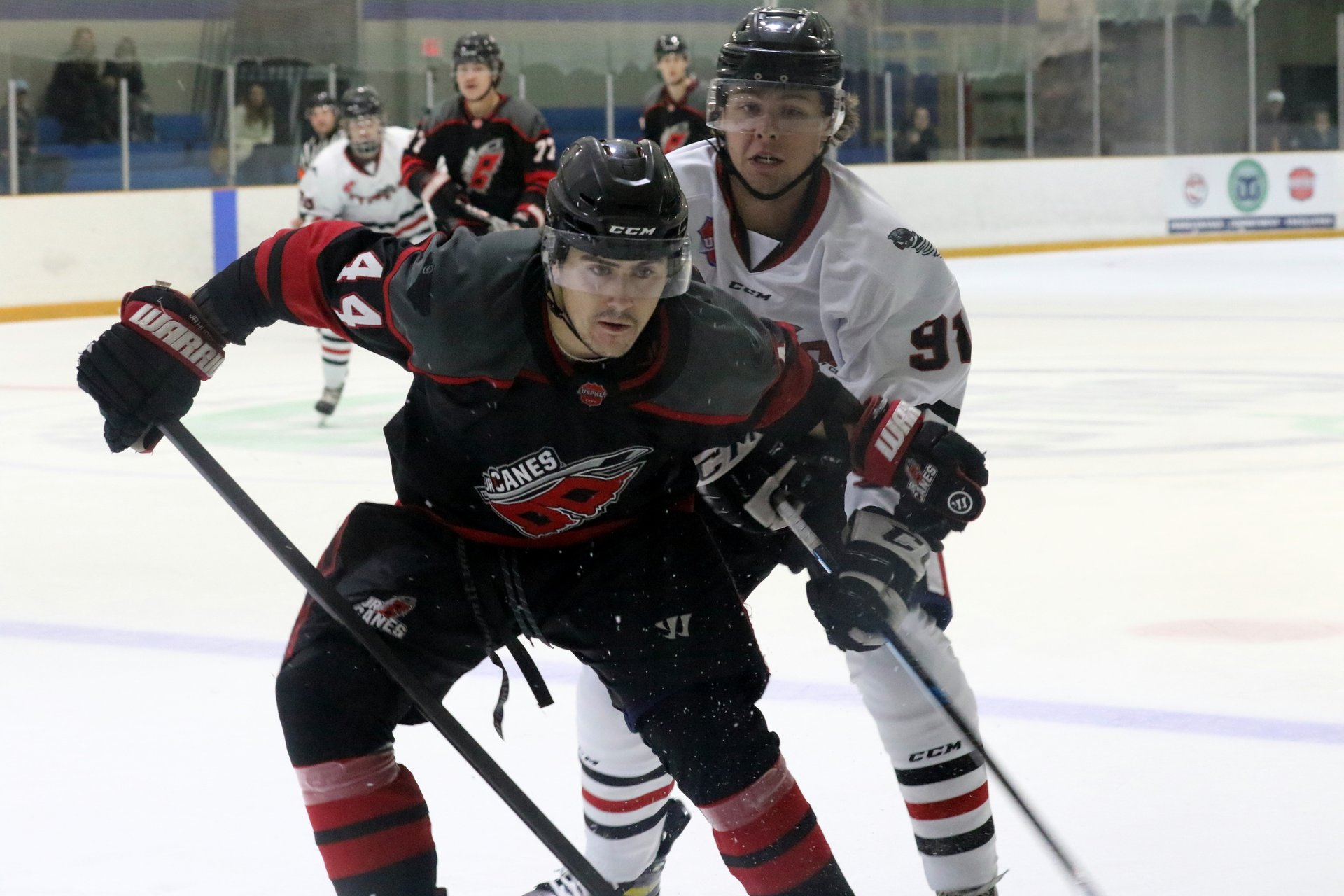 Derwin Hauser skating for the puck with defender trying to stop him
