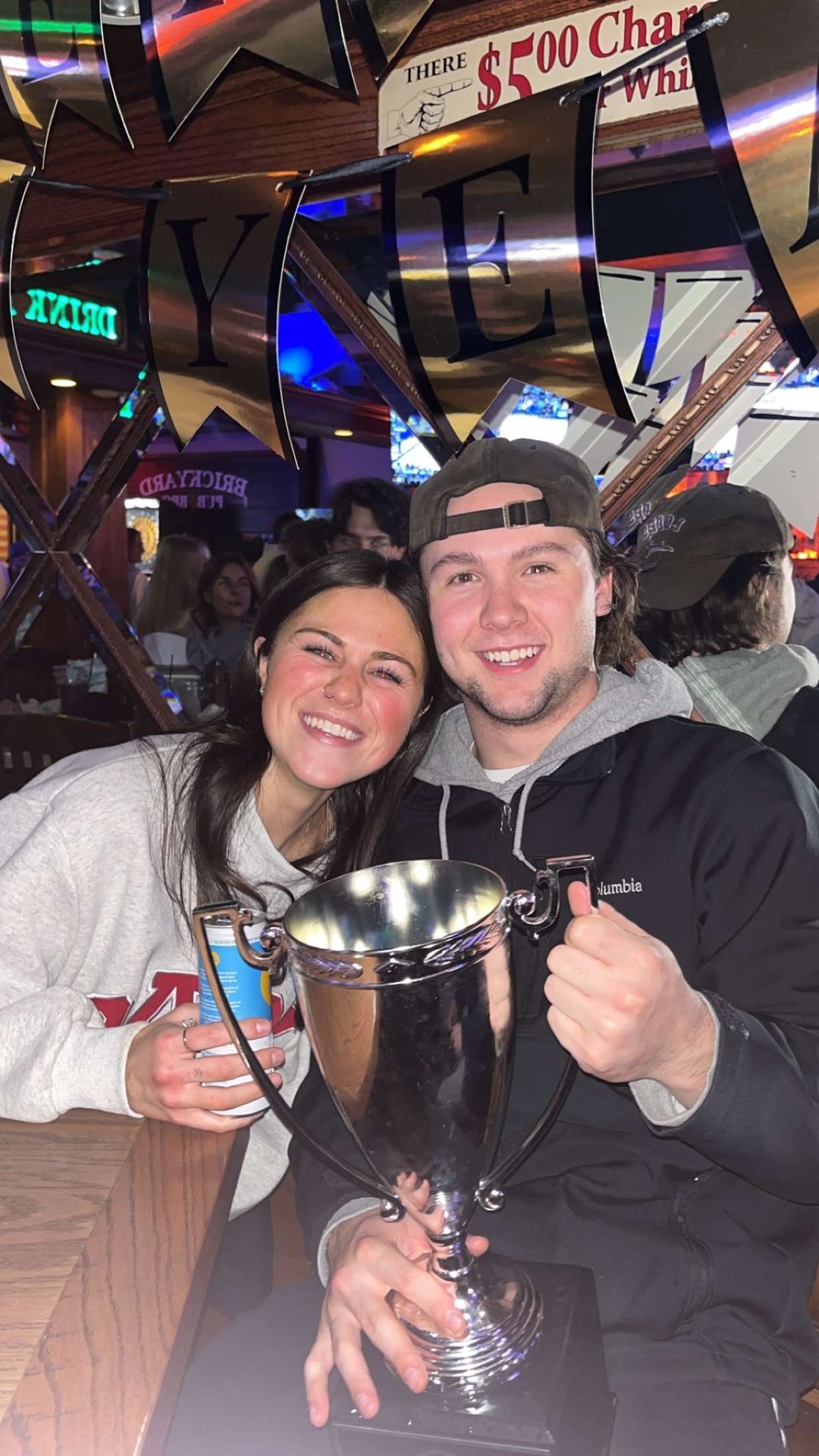 Derwin Hauser and Emily holding a trophy in a crowded bar