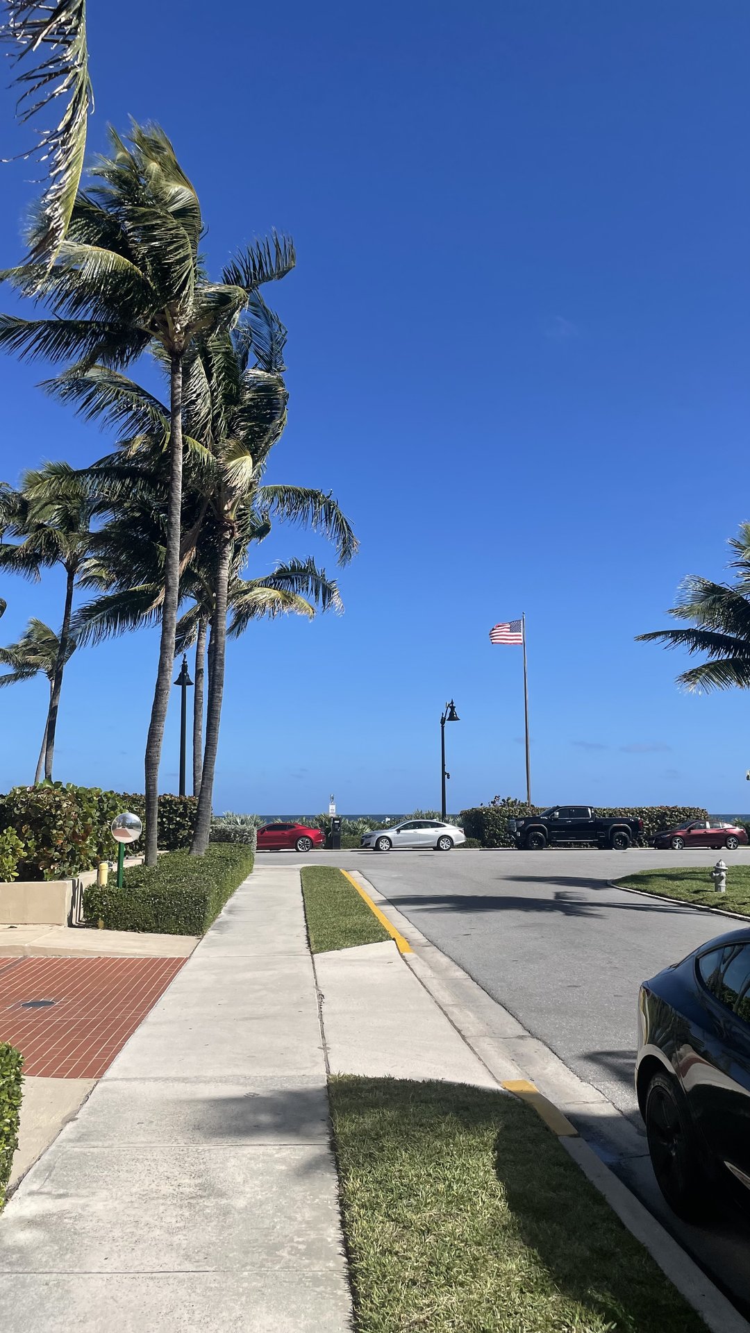 sidewalk leading to beach with american flag flying high on a flagpole