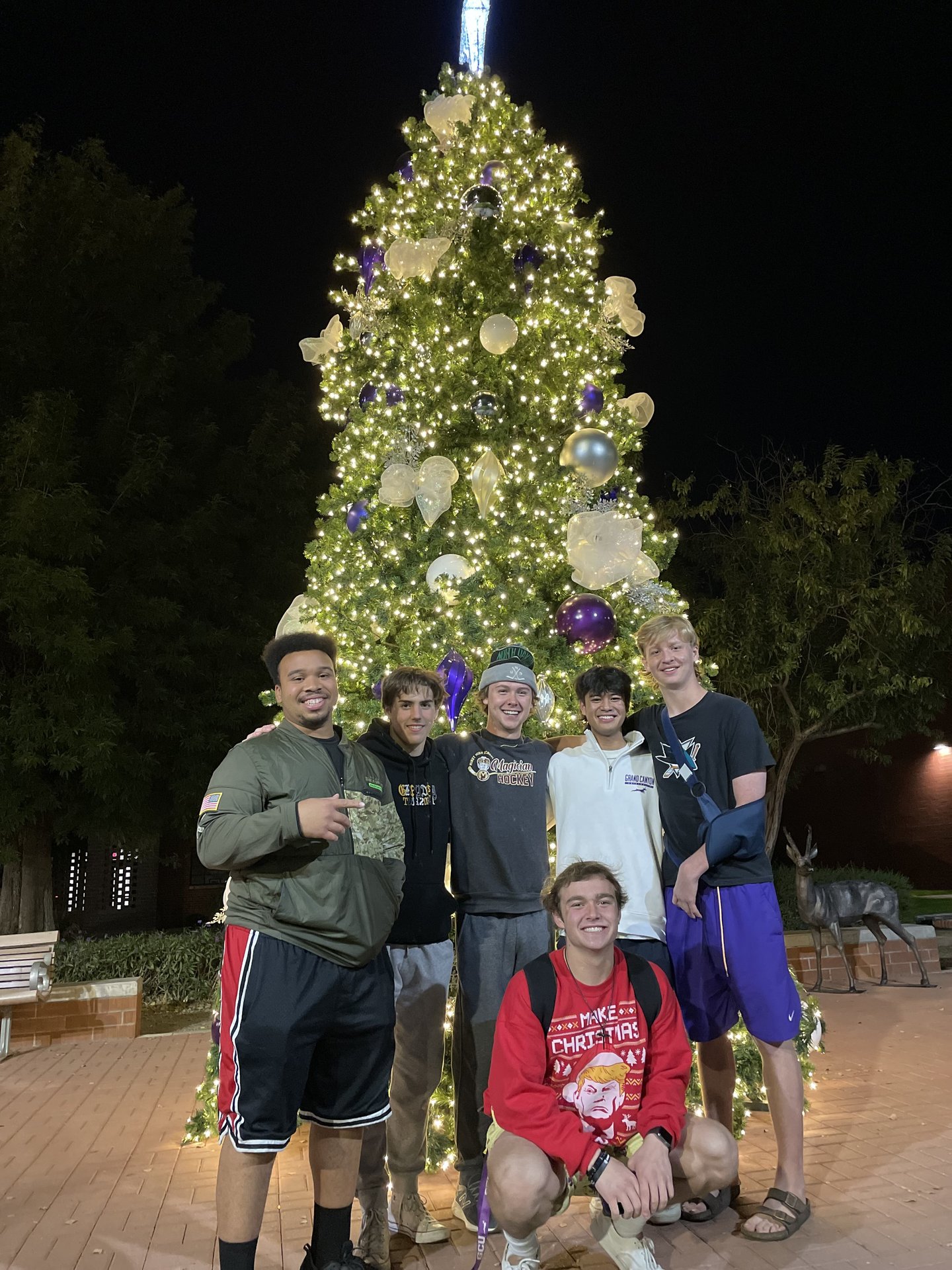 Derwin Hauser with friends in front of brightly lit Christmas tree