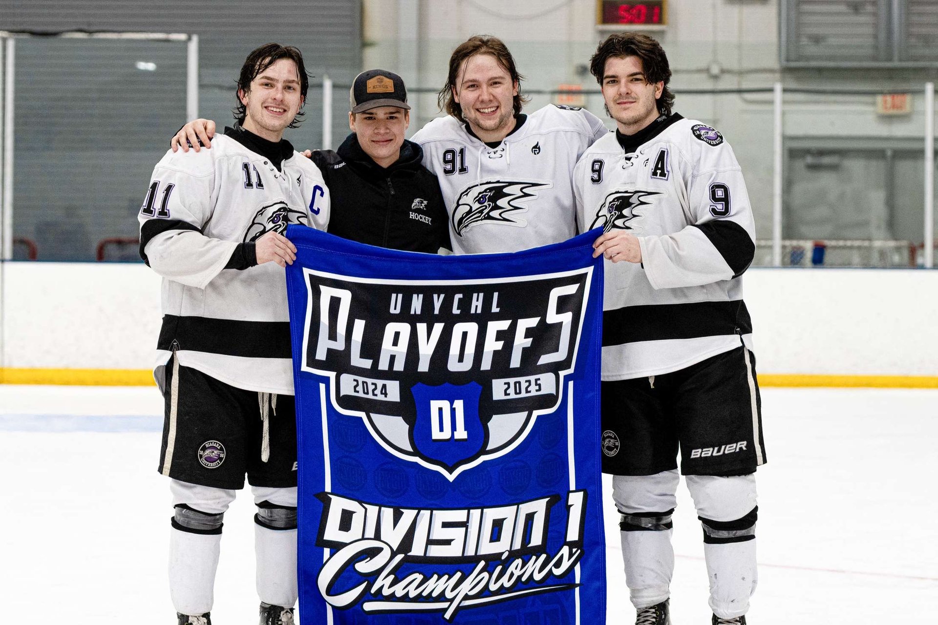 four hockey teammates holding championship banner